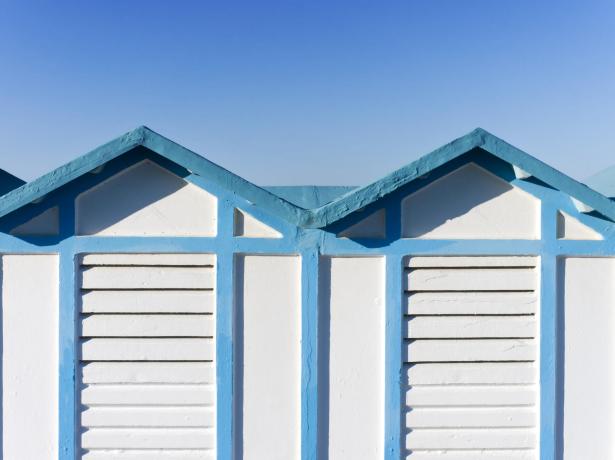 Cabine da spiaggia bianche e blu sotto un cielo limpido.
