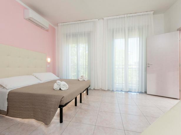 Camera luminosa con letto matrimoniale e tende bianche.