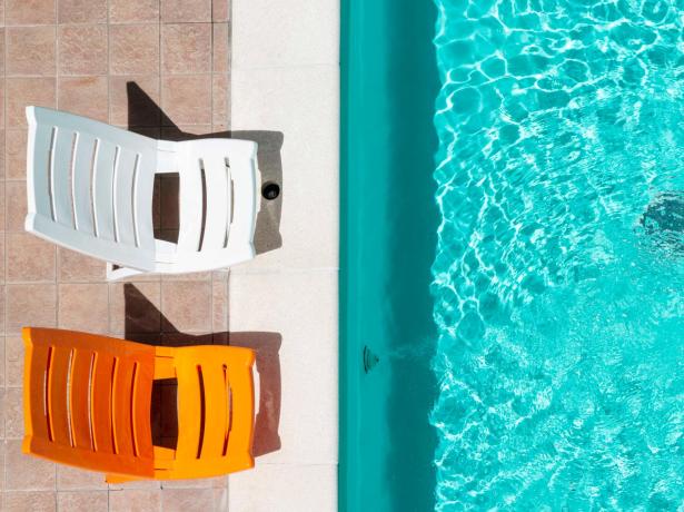 Due sedie colorate accanto a una piscina luminosa.