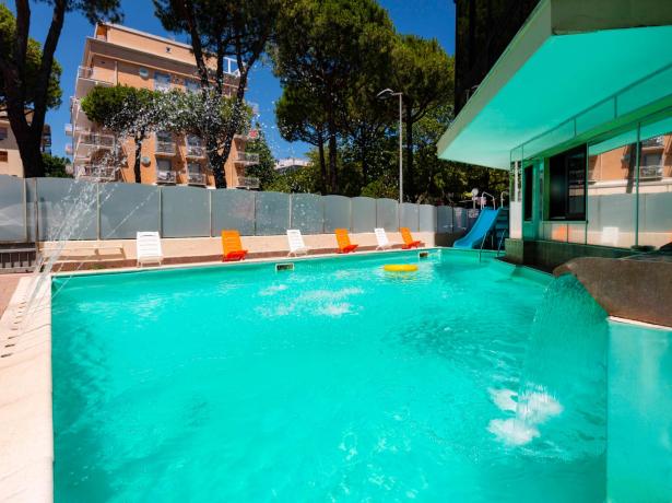 Piscina all'aperto con sedie a sdraio e scivolo.