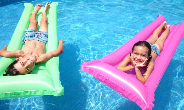 Due bambini su materassini colorati in piscina.