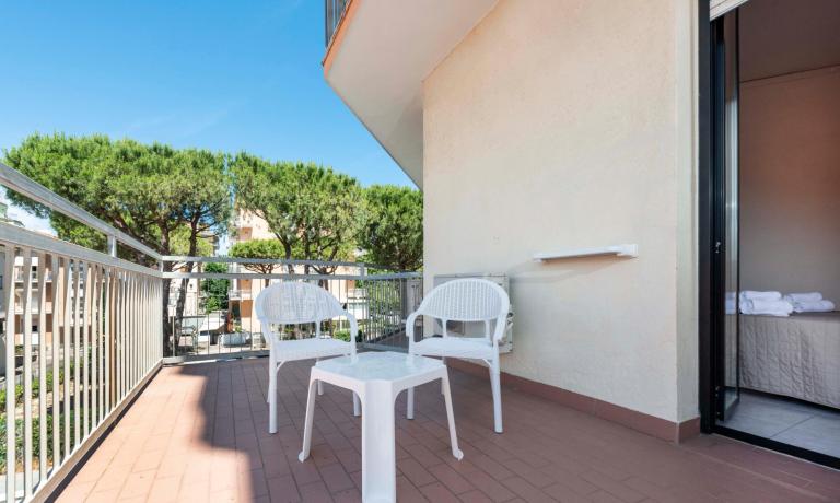 Terrazza con sedie bianche e tavolo, vista alberi.